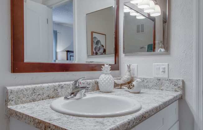 Master bathroom with floating vanities, quartz countertops, backlit vanity mirror, walk in shower with Euro shower door and quartz topped bench seat at Nob Hill Apartments, Nashville