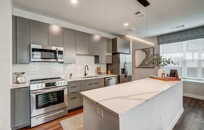 the kitchen has stainless steel appliances and a large white island