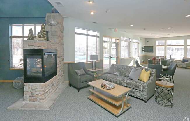 A living room with a stone fireplace and grey couches.