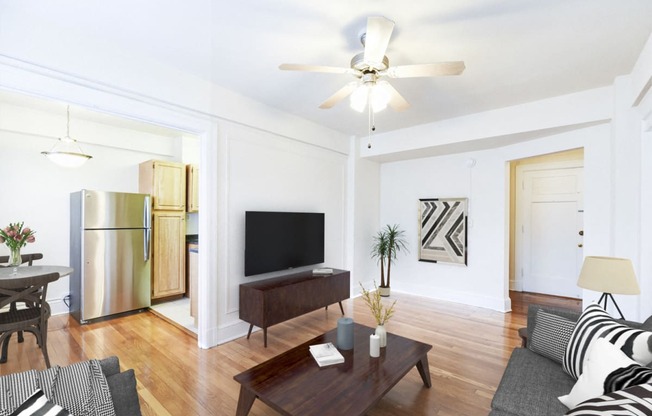 living area with sofa, coffee table, credenza, tv, hardwood floors, ceiling fan and view of kitchen at wakefield apartments in washington dc