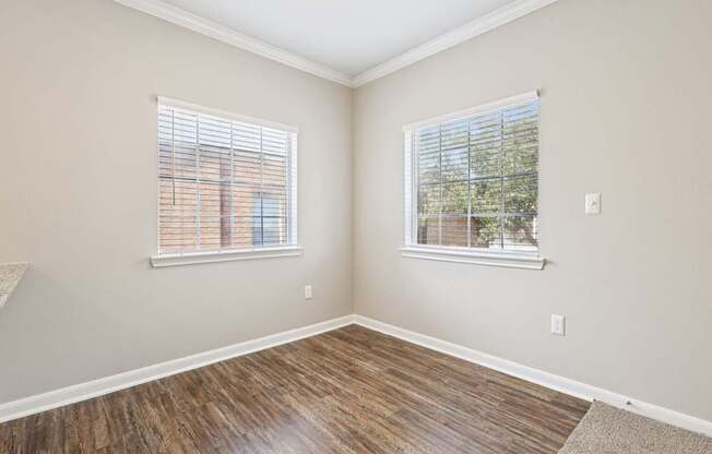 A room with wooden floors and two windows.