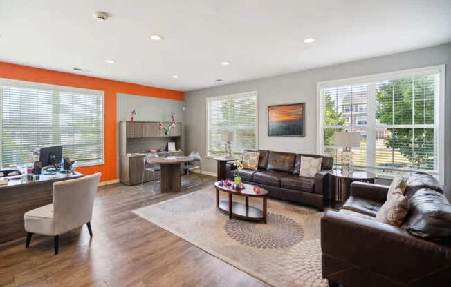 A living room with a brown leather couch and a wooden floor.