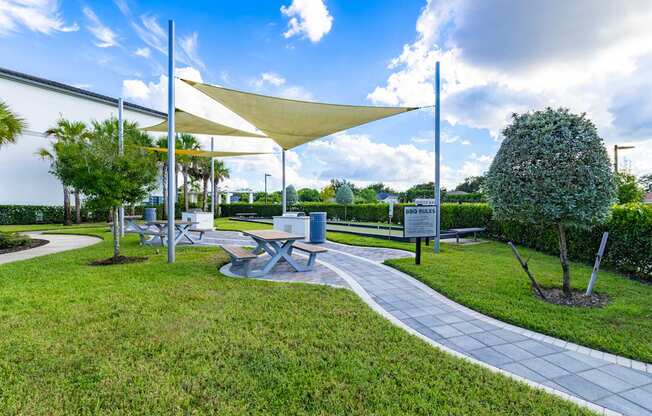A park with a walkway, trees, and a white canopy.