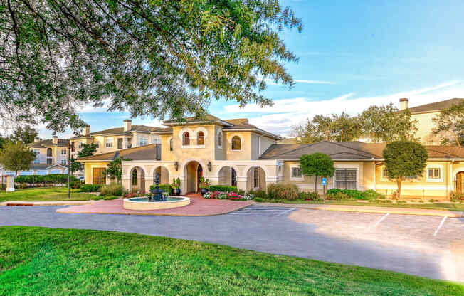 A large house with a circular driveway and a fountain in the middle.