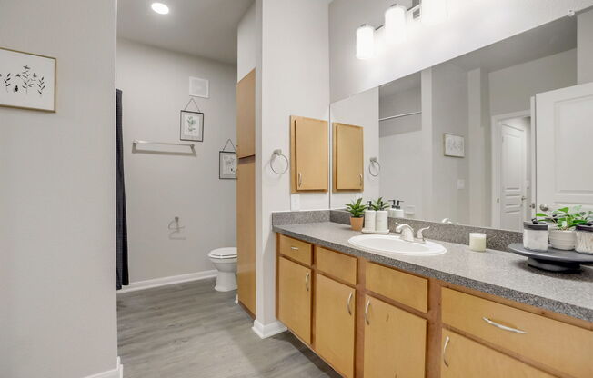 A bathroom with a toilet, sink, and mirror.