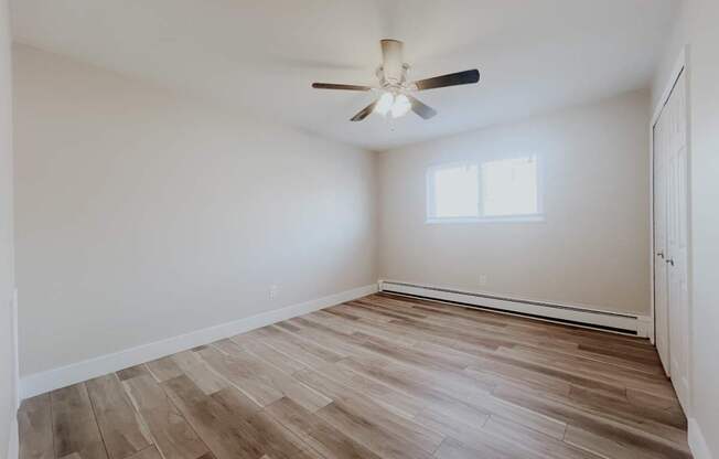 A room with a ceiling fan and wooden flooring.