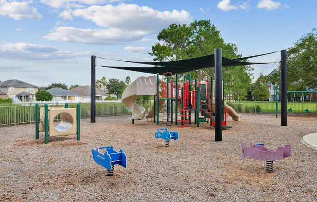 A playground with a slide and swings at Wynnfield Lakes Apartments in Jacksonville, FL