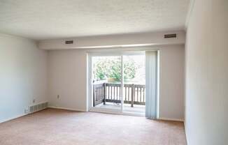 A room with a carpeted floor and a view of a balcony with a railing at Hummingbird Pointe & The Gardens, Parma, OH