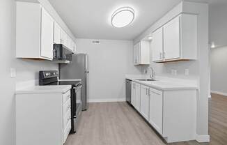 A kitchen with white cabinets and a stainless steel refrigerator.