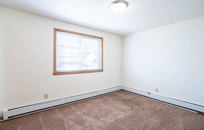 A room with a window and carpeted floor. Fargo, ND Birchwood 2 Apartments