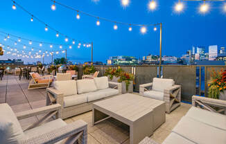 a rooftop terrace with couches and tables and a city skyline