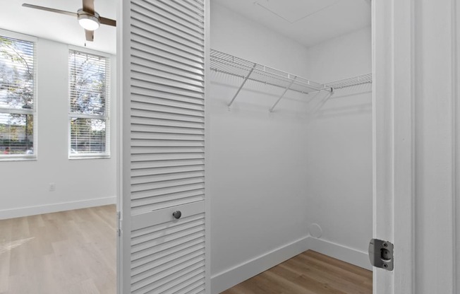 a closet in a bedroom with white walls and wood floors at One Plantation in Plantation, FL