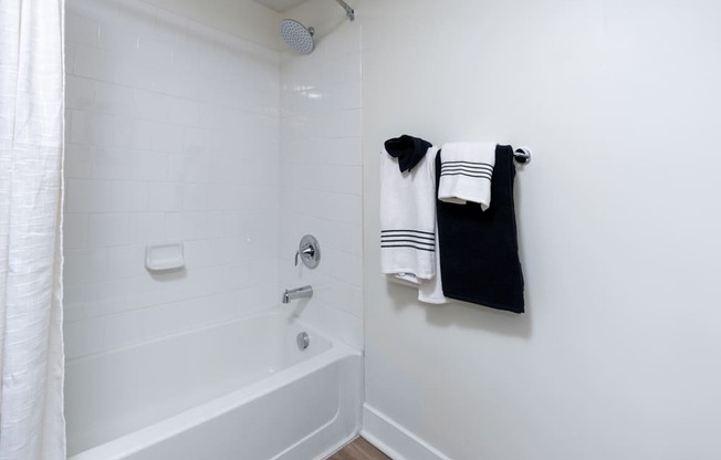 A white bathroom with a white tub and a white shower curtain.