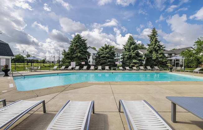 A pool surrounded by trees and chairs