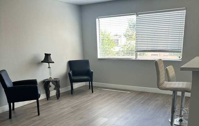 A room with a grey floor and a window with blinds.