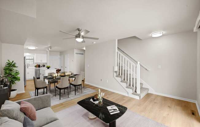 the living room and dining area of a home with a staircase and a dining table