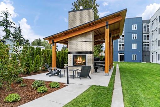 A modern outdoor patio with a fireplace and seating area.