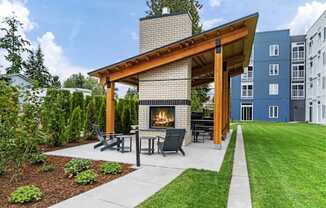 A modern outdoor patio with a fireplace and seating area.