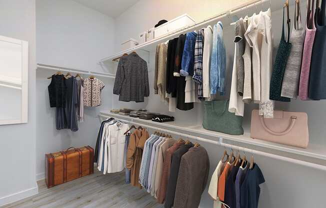 a walk in closet with white shelves and rails and a white shelf with clothes hanging on it