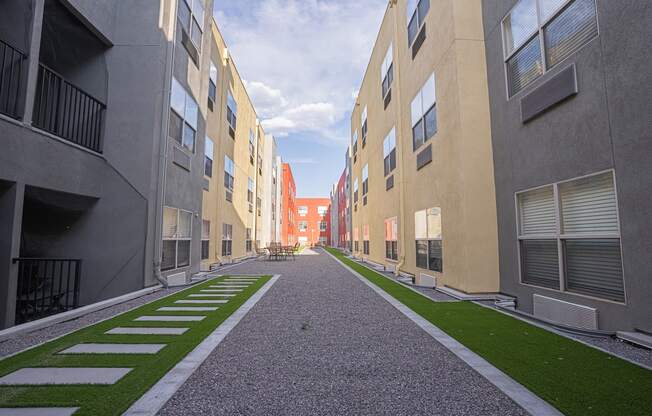 a view of a courtyard between two apartment buildings with grass