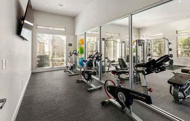 A gym with a mirrored wall and various exercise equipment.