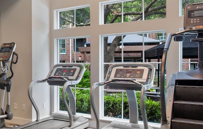 a gym with cardio machines and a large window