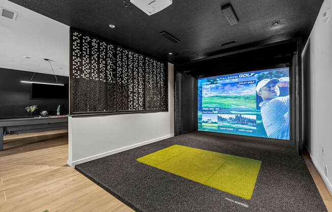 a living room with a large screen on the wall and a yellow rug