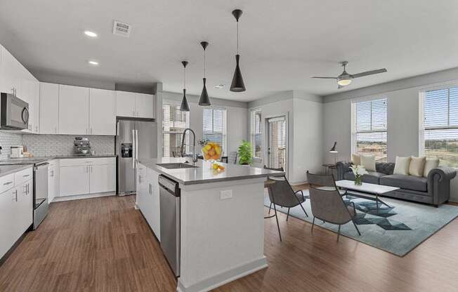 A modern kitchen with white cabinets and a wooden floor.