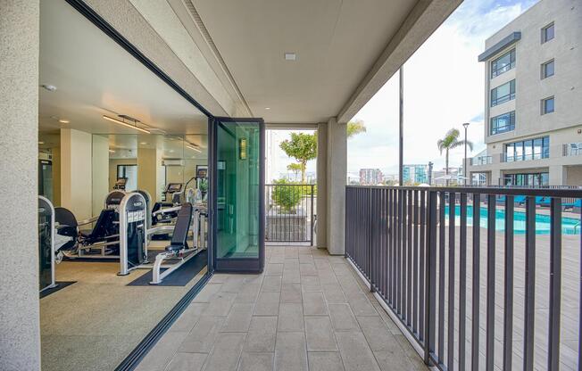 Fitness center with a covered patio and open views connecting indoor workouts to the pool deck.