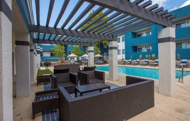 a patio with a pool and chairs under awning