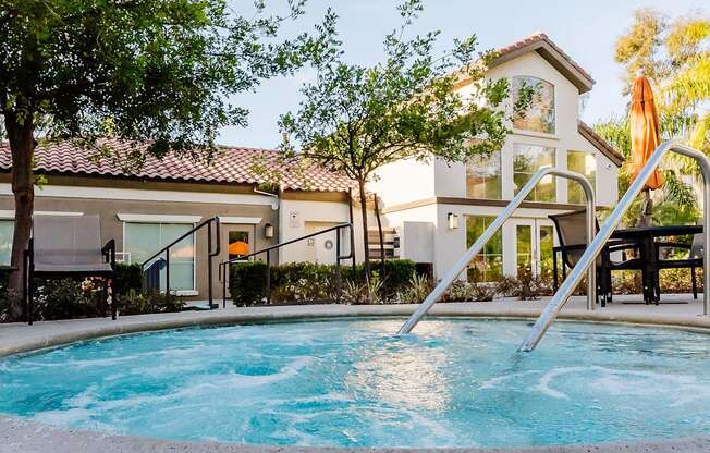 A swimming pool in front of a house with a staircase leading to the house.