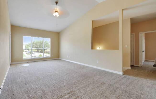 A spacious room with a carpeted floor and a ceiling fan.