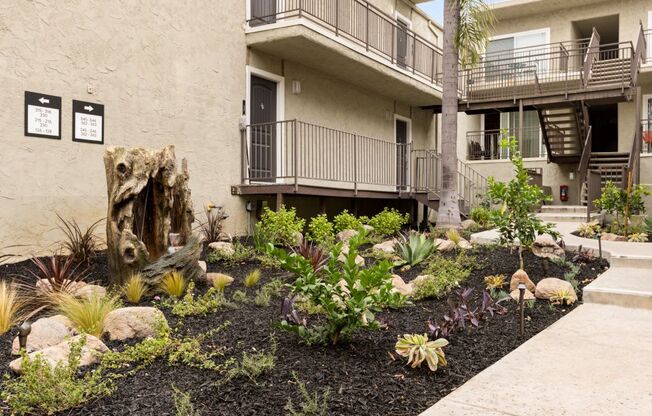 the front yard of an apartment building with landscaping and rocks