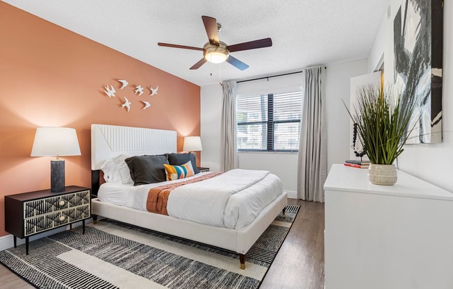 A bedroom with a white bed and a ceiling fan.