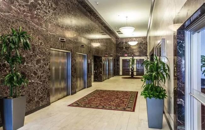 A hallway with marble walls and a red rug.