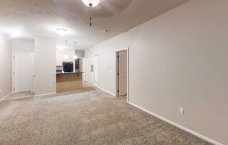 an empty living room and kitchen with a carpeted floor