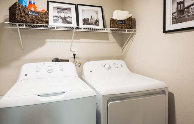 a washer and dryer in a laundry room with pictures on the wall