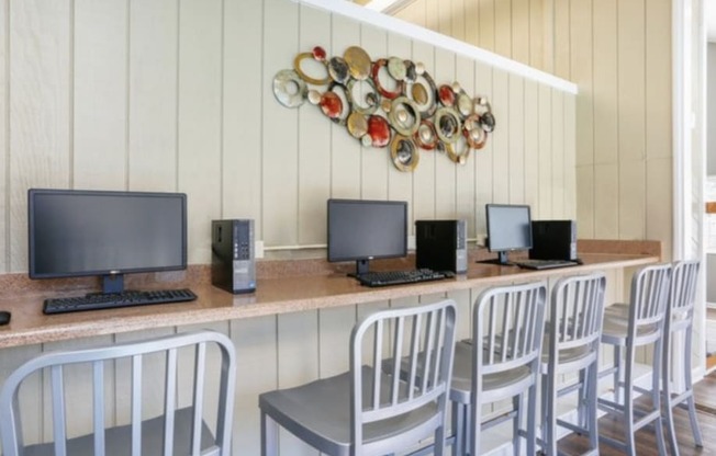 a desk with computers and chairs in a room