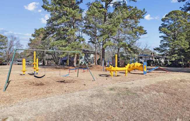 A playground with a yellow swing set and a blue slide.