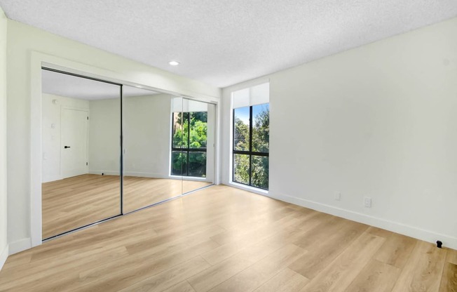 an empty living room with wood floors and sliding glass doors