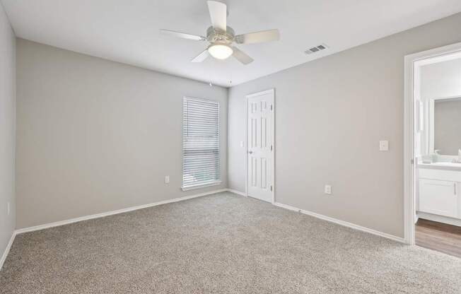 A room with a ceiling fan and carpeted floor.
