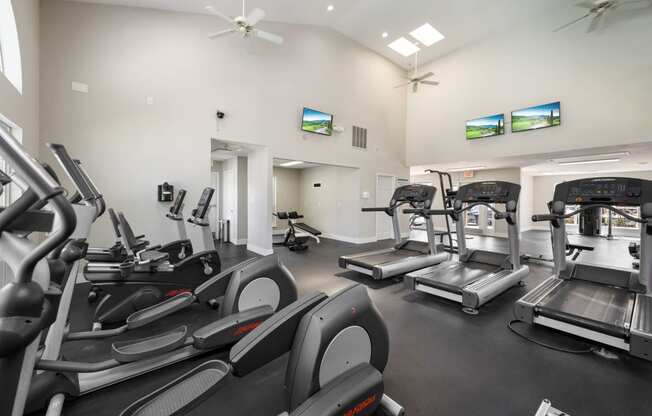 a gym with cardio equipment and flat screen tvs