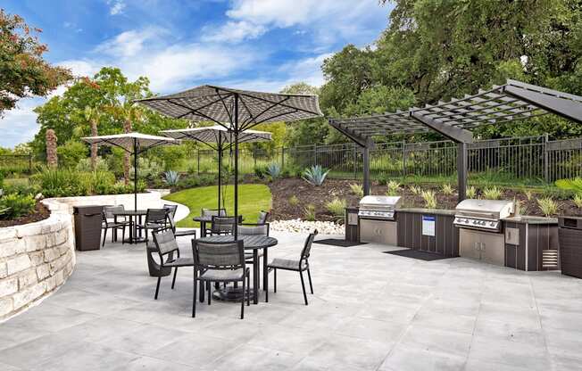 an outdoor patio with a grill and tables and umbrellas