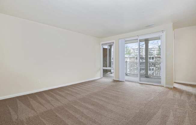 an empty living room with a sliding glass door to a balcony