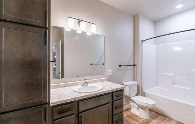 a bathroom with a sink and a toilet and a shower. Fargo, ND Prairiewood Meadows Apartments