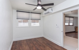an empty living room with a ceiling fan and windows