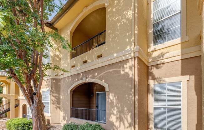 a building with a balcony and a tree in front of it