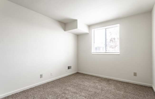 an empty room with white walls and a window