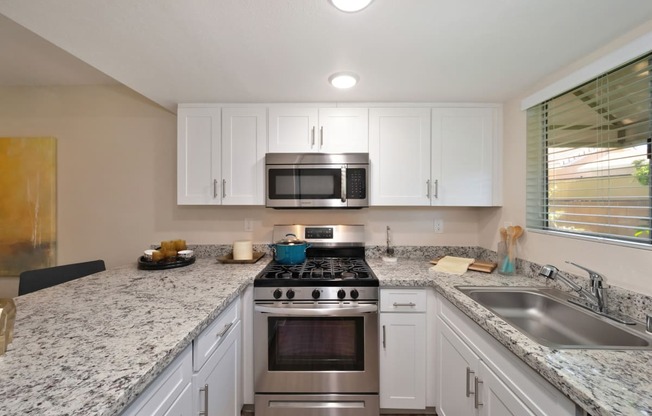 a kitchen with white cabinets and granite countertops