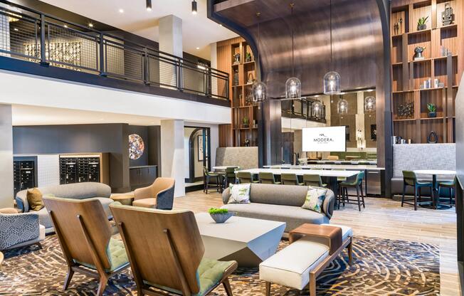 Double-height community lounge with layered seating, a shared kitchen, and warm wood details designed for conversation, hosting, and everyday gathering.